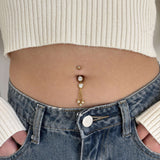 Navel piercing with heart and gold pendants